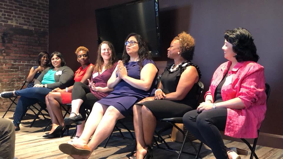 Yaya speaking on a panel with a group of women.